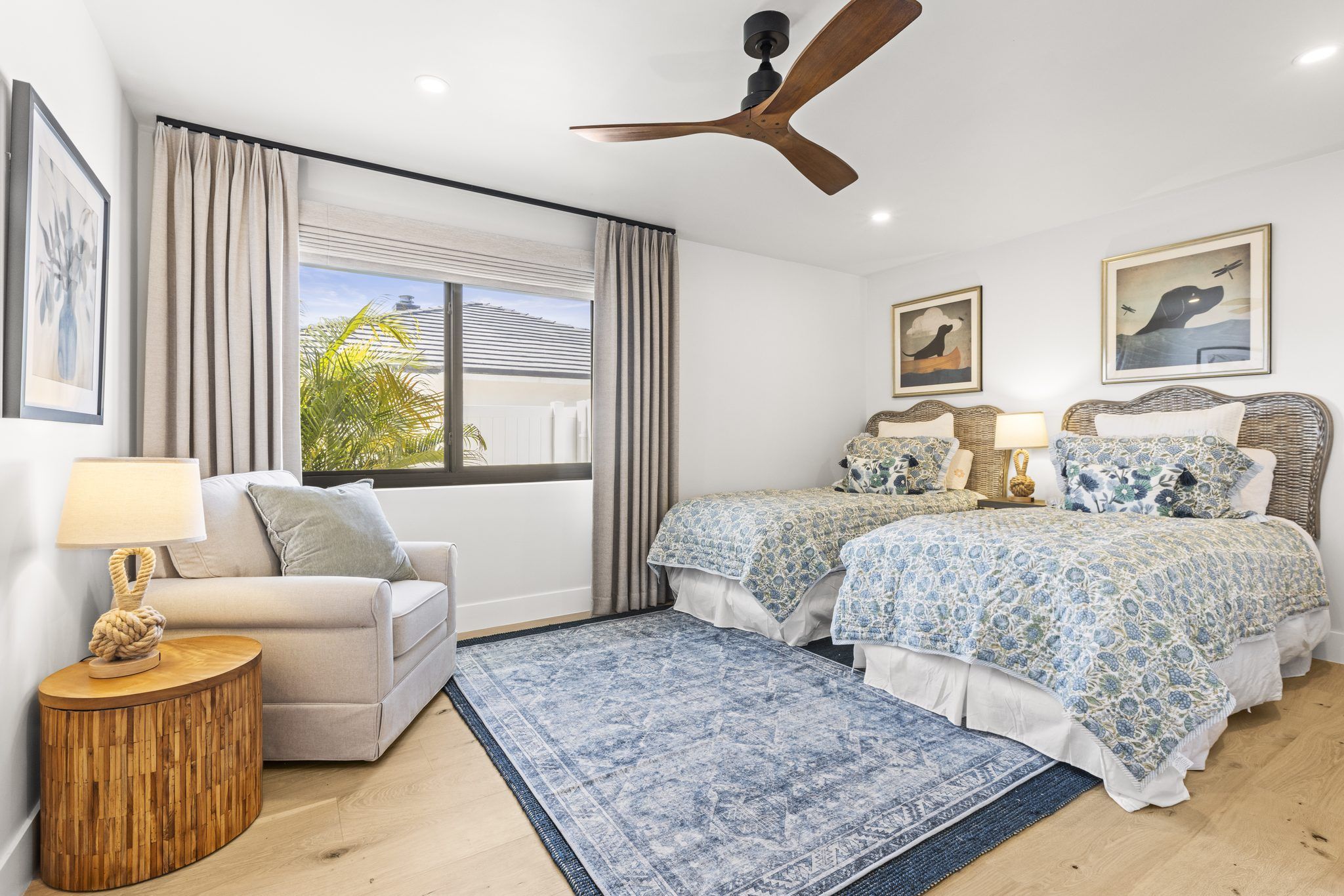 Staged bedroom with neutral bedding, an armchair and a bright window