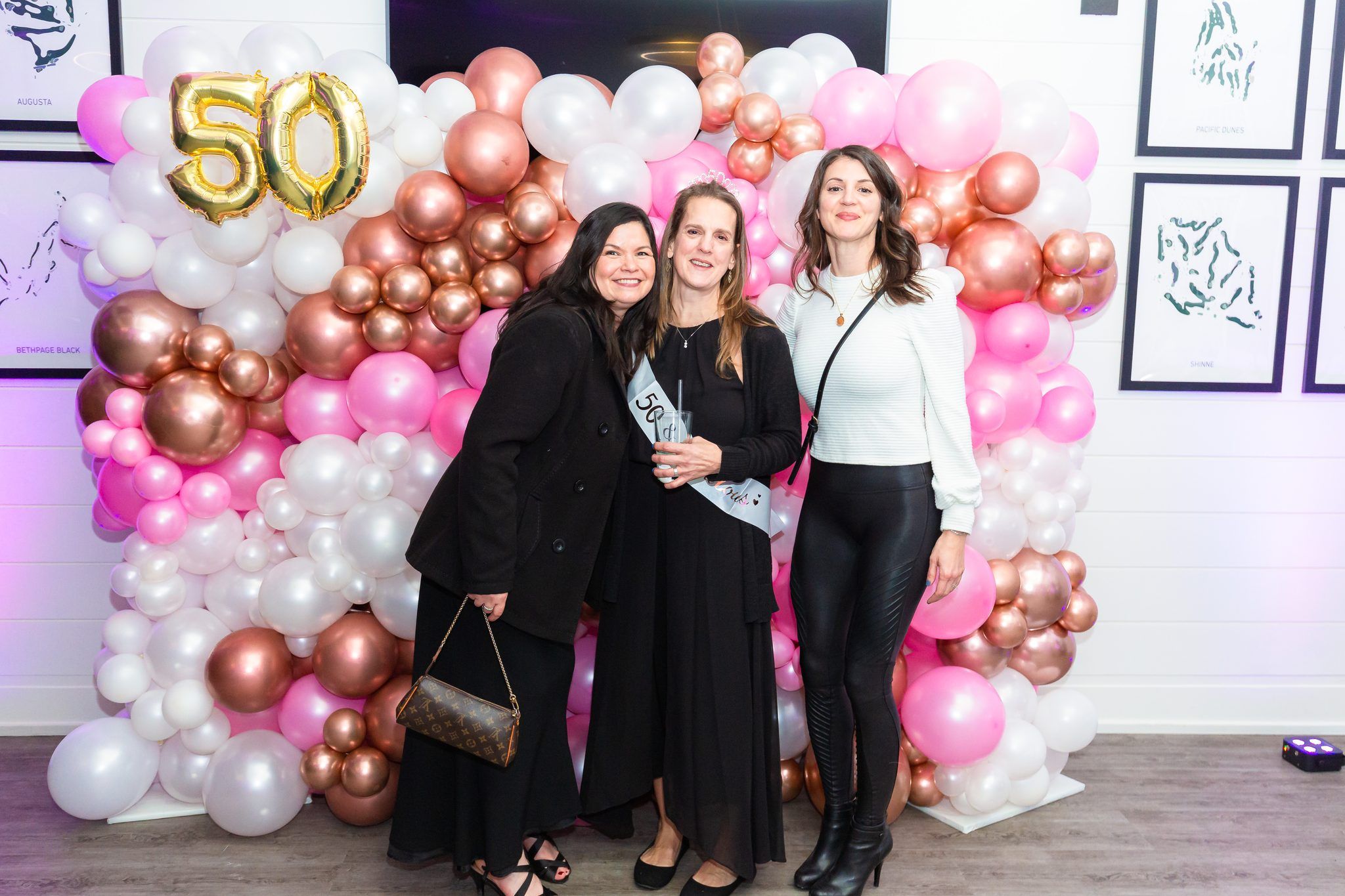Two women by gold happy birthday balloons