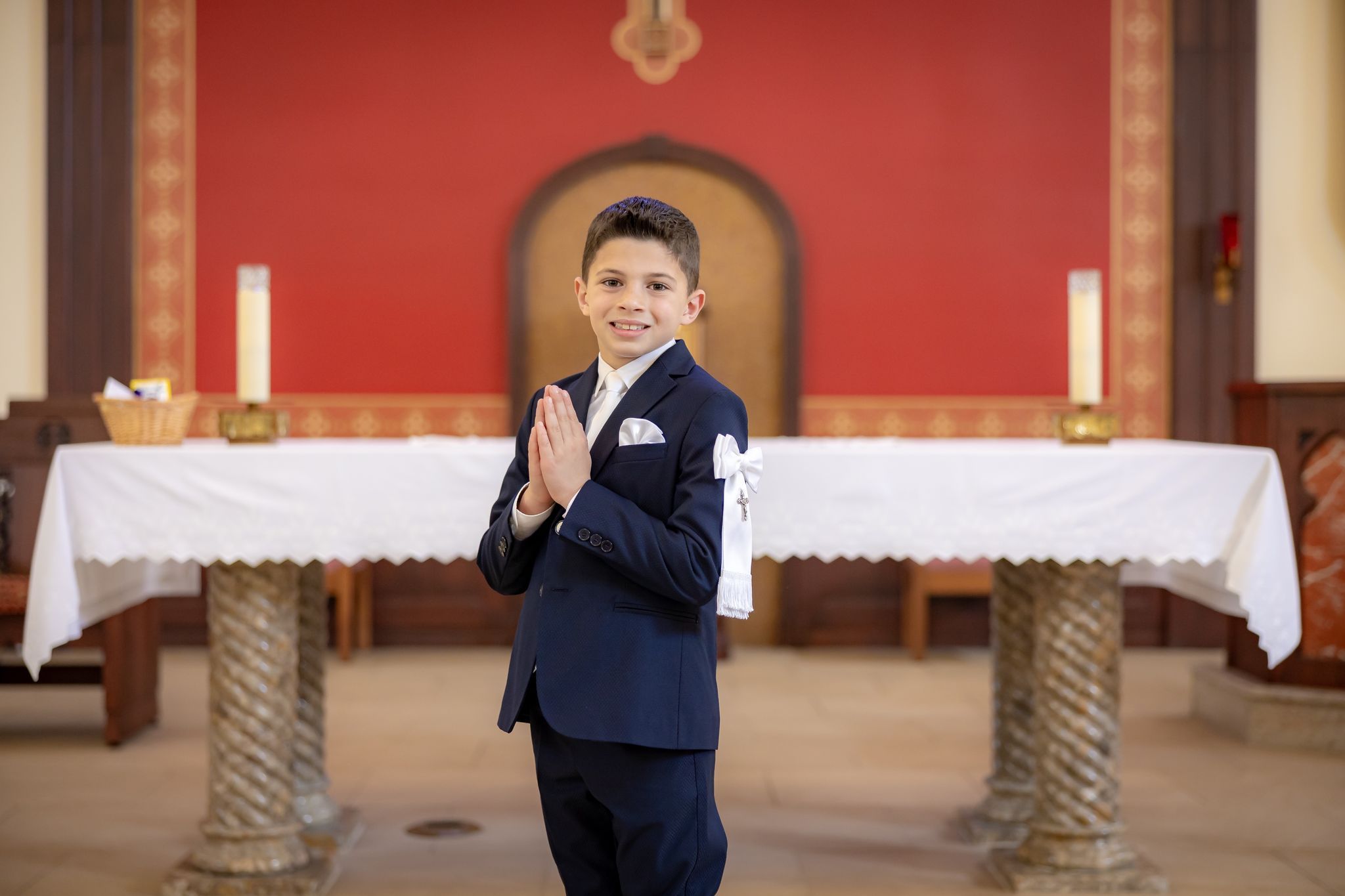 Boy in communion suit praying at church altar
