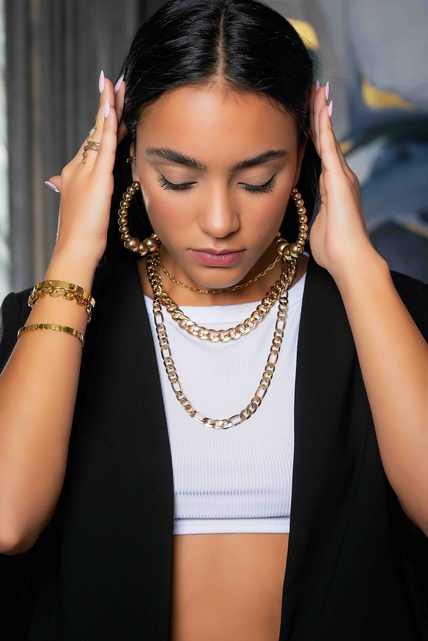 Model wearing gold hoops and layered chains