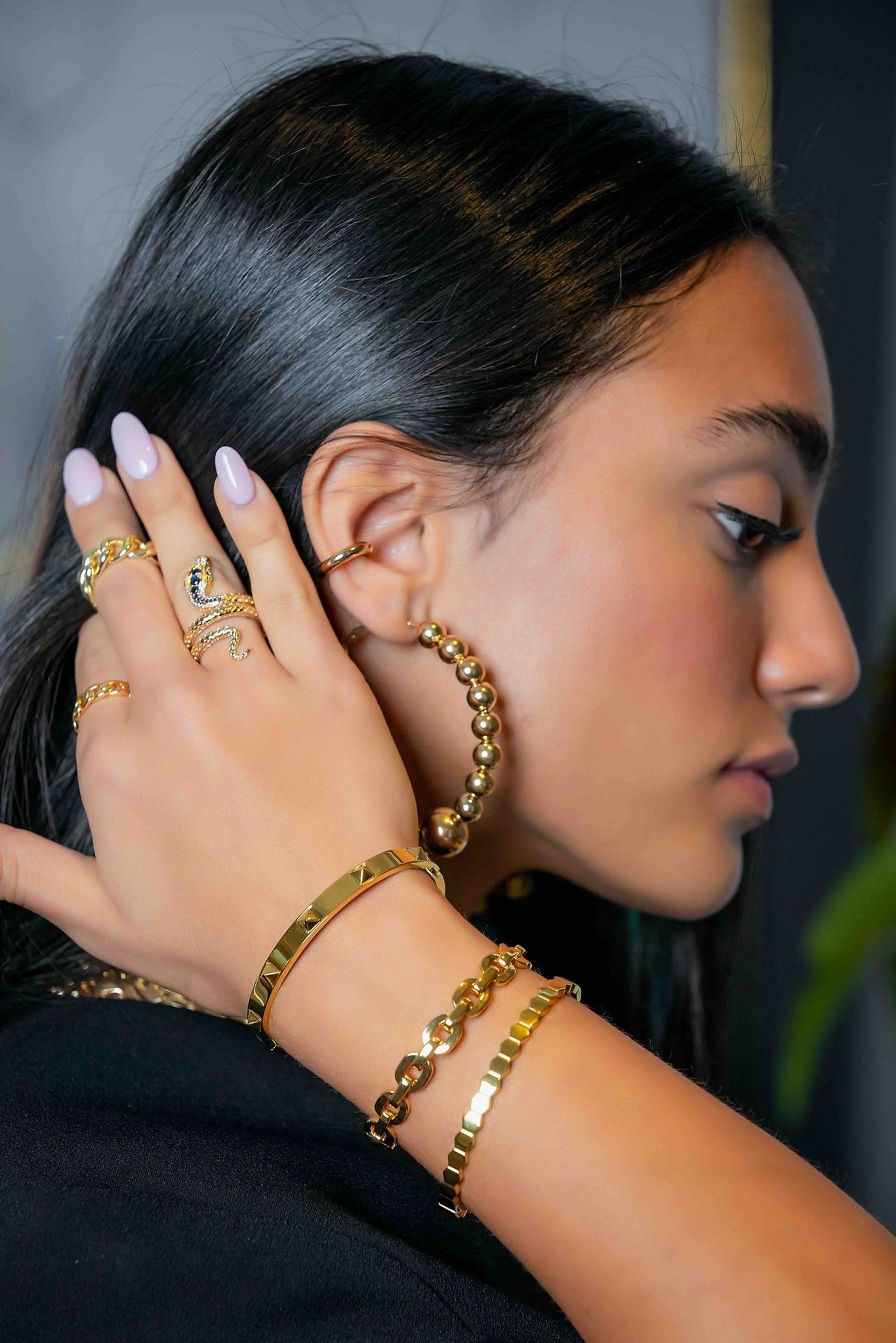 Side profile of model wearing gold hoop earring and bracelets